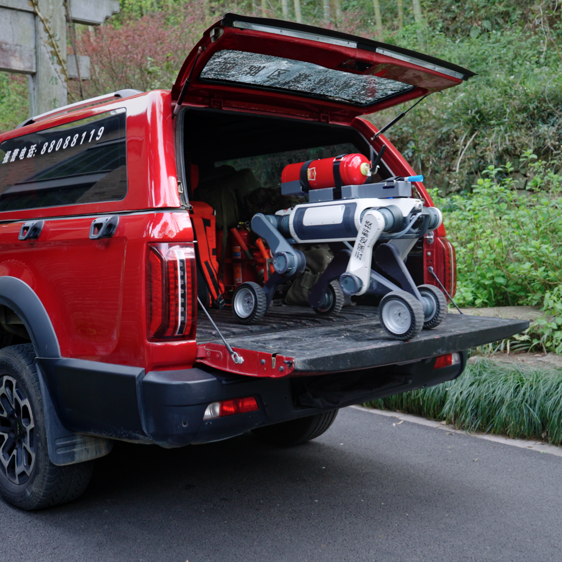 DEEP Robotics Lynx M20 Pro wheel-legged robot with a fire extinguisher module on its back, being transported in the open tailgate of a red pickup truck. The robot is designed for industrial inspection, emergency rescue, and navigating hazardous, all-terrain environments using advanced features like LiDAR and autonomous navigation.