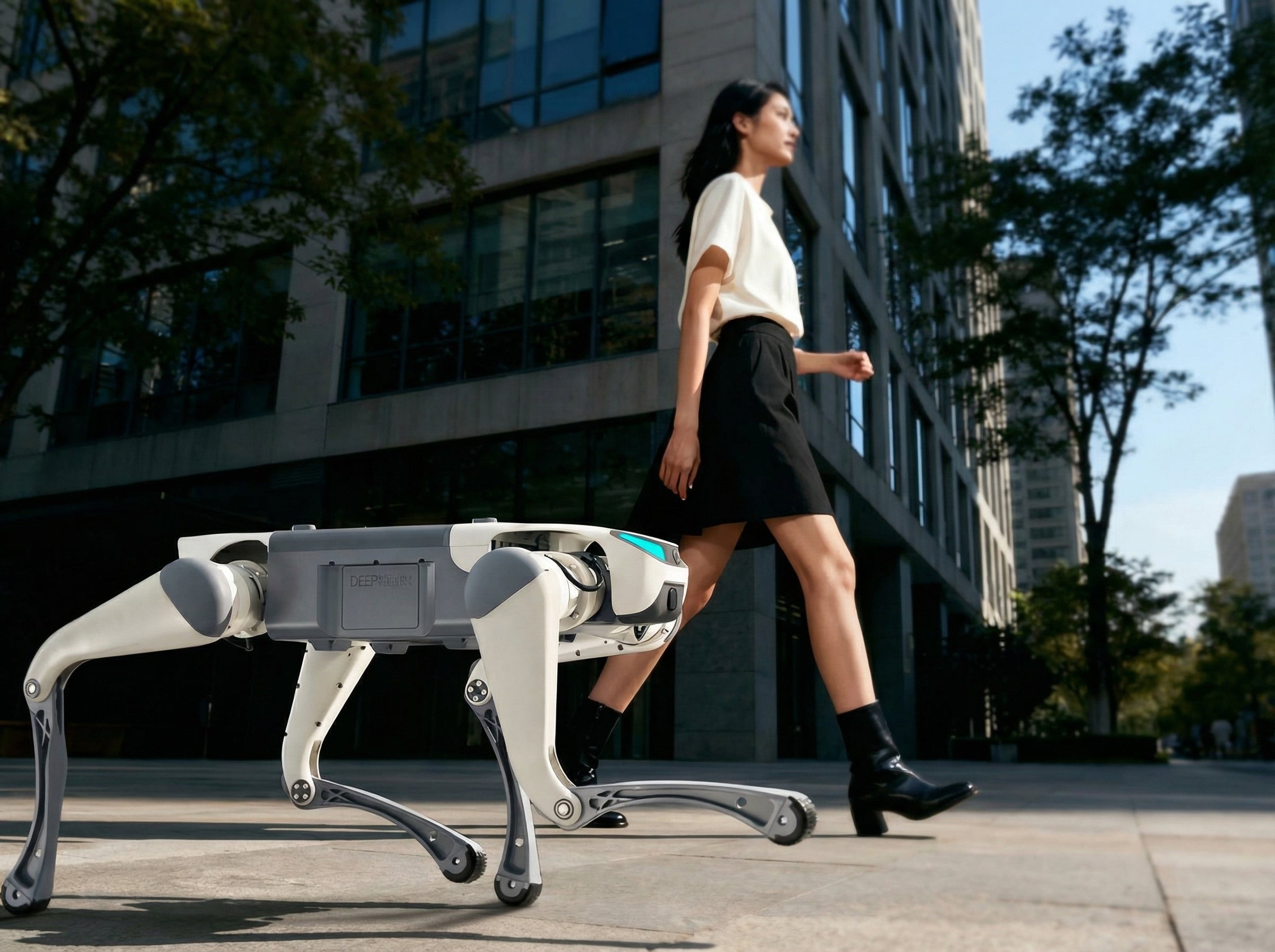 A DEEP Robotics Lite3 quadruped robot, featuring a sleek white and grey design with wheels on its feet, walks autonomously alongside a person on a paved path in an urban setting. This AI-powered robotic dog is designed for education, research, and as a personal companion, demonstrating its advanced mobility and integration into everyday life for tasks like assistance and carrying items.