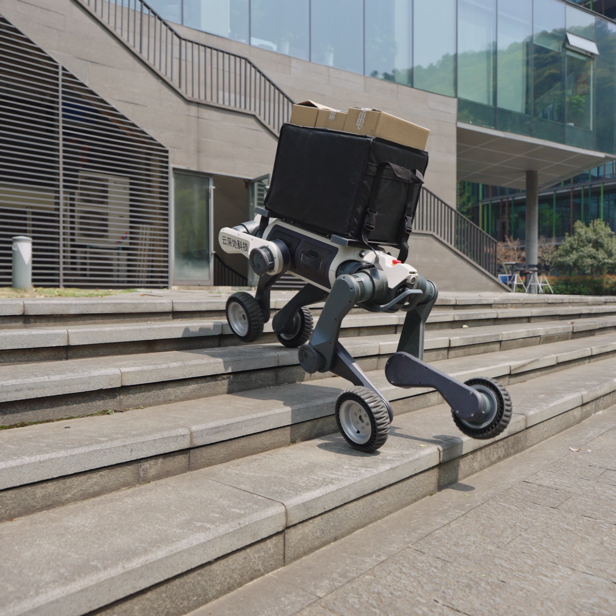 A DEEP Robotics Lynx M20 Pro, a hybrid wheeled-legged quadruped robot, is shown climbing concrete stairs while carrying a black delivery bag with cardboard boxes on top. The robot demonstrates its advanced mobility and IP66 protection for last-mile logistics and navigating complex outdoor environments.