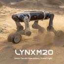 A DEEP Robotics Lynx M20 wheel-legged quadruped robot navigates a sandy desert environment, kicking up dust. The robot is designed for omni-terrain operations, industrial inspection, and emergency rescue in challenging and hazardous environments, combining the speed of wheels with the agility of legs.